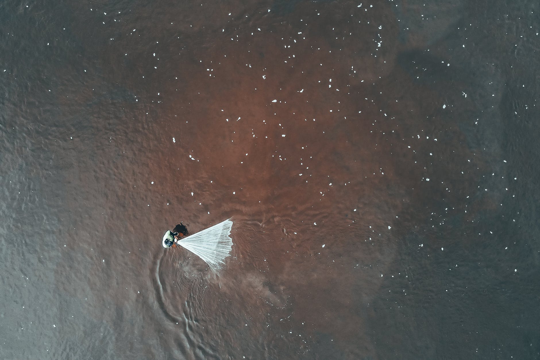 unrecognizable person fishing with net in dirty sea